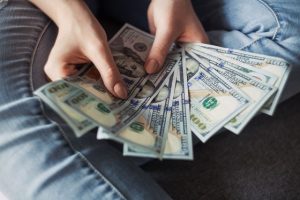 Image of hands holding several 100 dollar bills